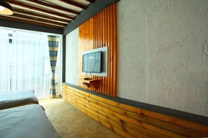 A hotel room with a bed, a television mounted on a wooden panel wall, and a window with curtains. - Dali Yunmu Inn (Dali City)