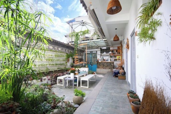 A courtyard with a dining area, potted plants, and a building with a blue door.