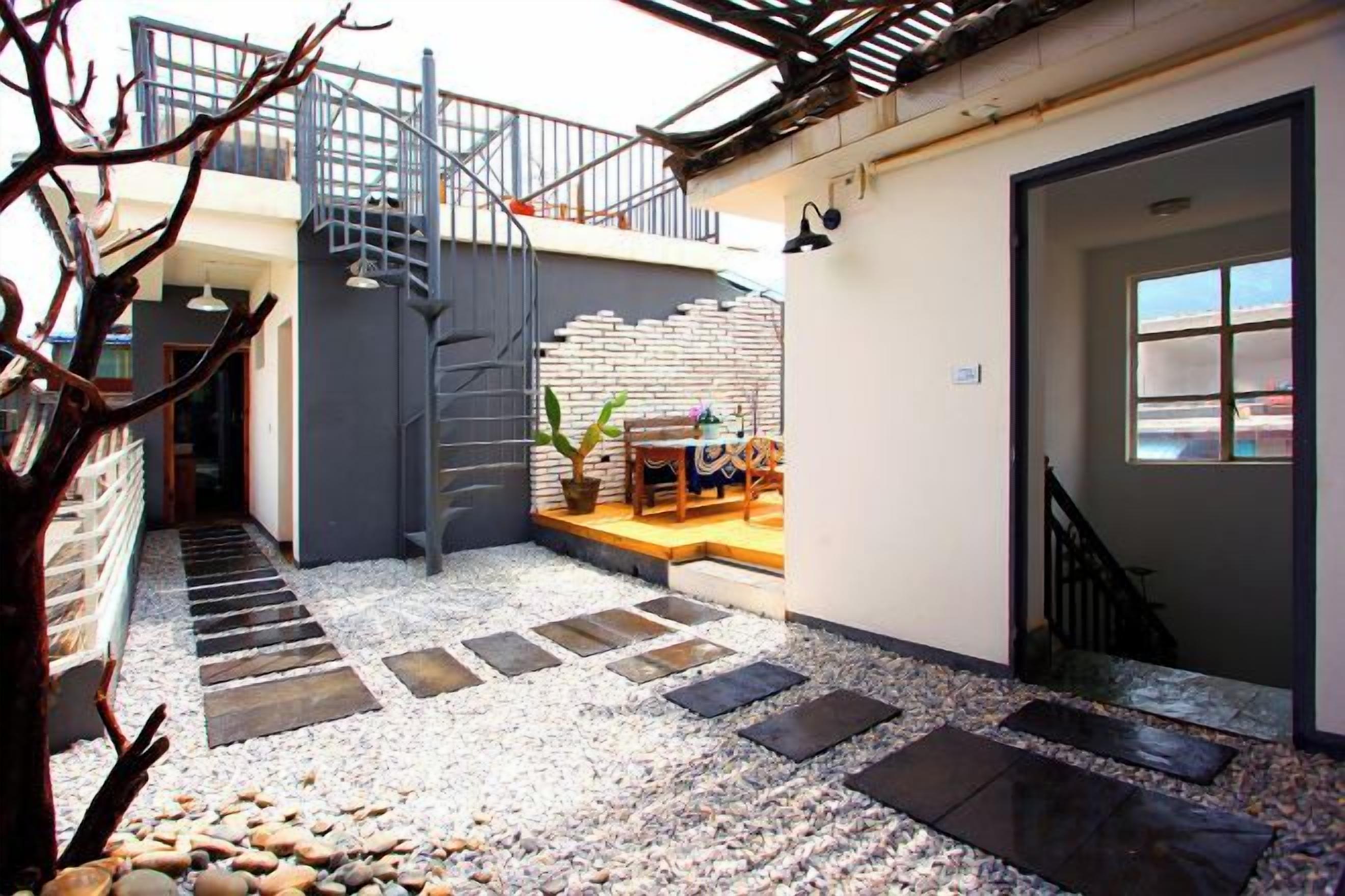 A courtyard with a staircase, a seating area, and a door leading to a room.