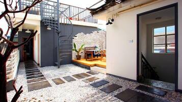 A courtyard with a staircase, a seating area, and a door leading to a room.