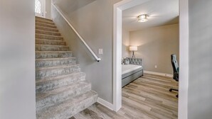 A staircase with carpeted steps leading to a room with a bed, a lamp, and a chair. - Charming Voyage: Ypsi & AnnArbor (Ypsilanti)