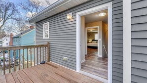 A house with a wooden deck, a door leading to a bedroom, and a visible chimney. - Charming Voyage: Ypsi & AnnArbor (Ypsilanti)
