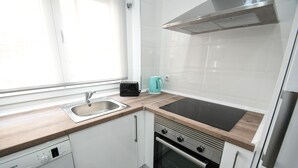 A modern kitchen with white cabinets, a Bosch dishwasher, a black induction cooktop, and a stainless steel range hood.
