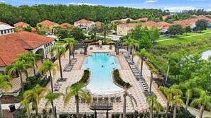 A resort with a central swimming pool, surrounded by palm trees and lounge chairs. - Family 6BR Resort Villa | Pool & Spa near Disney (Kissimmee)