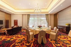A hotel room with a dining area featuring a round table, chairs, and a chandelier. - Juncheng Higher-quarter Hotel (Zhongshan)