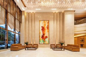 Eine Lobby mit großem Fenster, einer Rezeption und einer Sitzecke mit Sofas.
