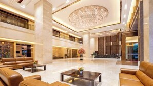 A spacious lobby with leather sofas, a coffee table, and a chandelier. - Juncheng Higher-quarter Hotel (Zhongshan)