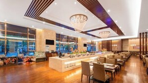 A modern restaurant with a central bar, wooden flooring, and large windows offering a view of the cityscape. - Juncheng Higher-quarter Hotel (Zhongshan)