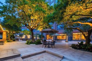An outdoor patio area with tables and chairs, surrounded by trees and buildings. - Juncheng Higher-quarter Hotel (Zhongshan)