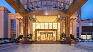A hotel entrance with a glass canopy, large doors, and a well-lit interior. - Juncheng Higher-quarter Hotel (Zhongshan)