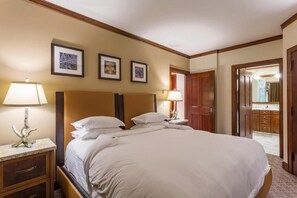 Habitación de hotel con una cama grande, dos mesitas de noche con lámparas, un cabecero de madera y cuadros enmarcados en la pared.