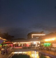 Hotel frente al mar con piscina, mobiliario exterior y estructuras iluminadas.