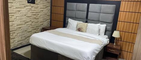 A bedroom with a bed, bedside table, and a wall-mounted air conditioner.