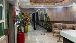 Eine Lobby mit einer Rezeption, einem Weihnachtsbaum und einem großen, roten Pflanzgefäß mit Pflanze.