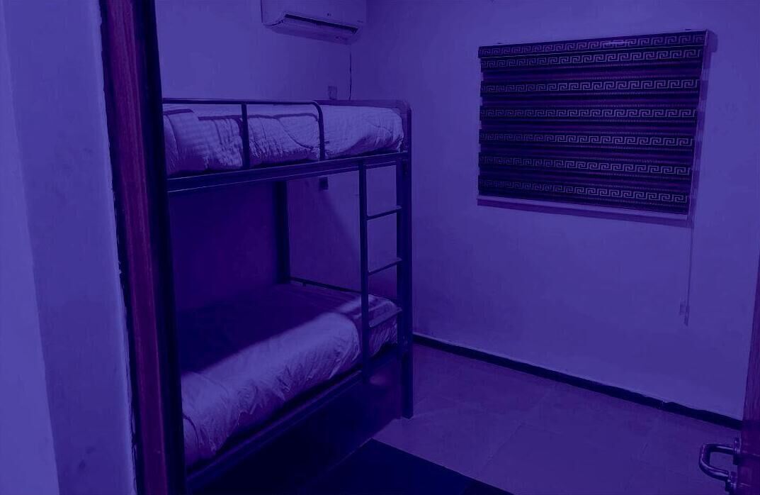 A bunk bed room with a patterned curtain and a small window.