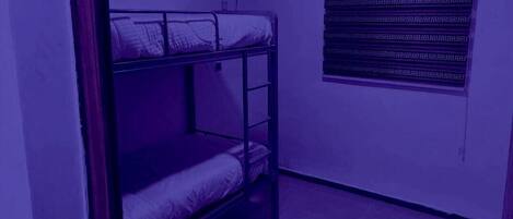 A bunk bed room with a patterned curtain and a small window.