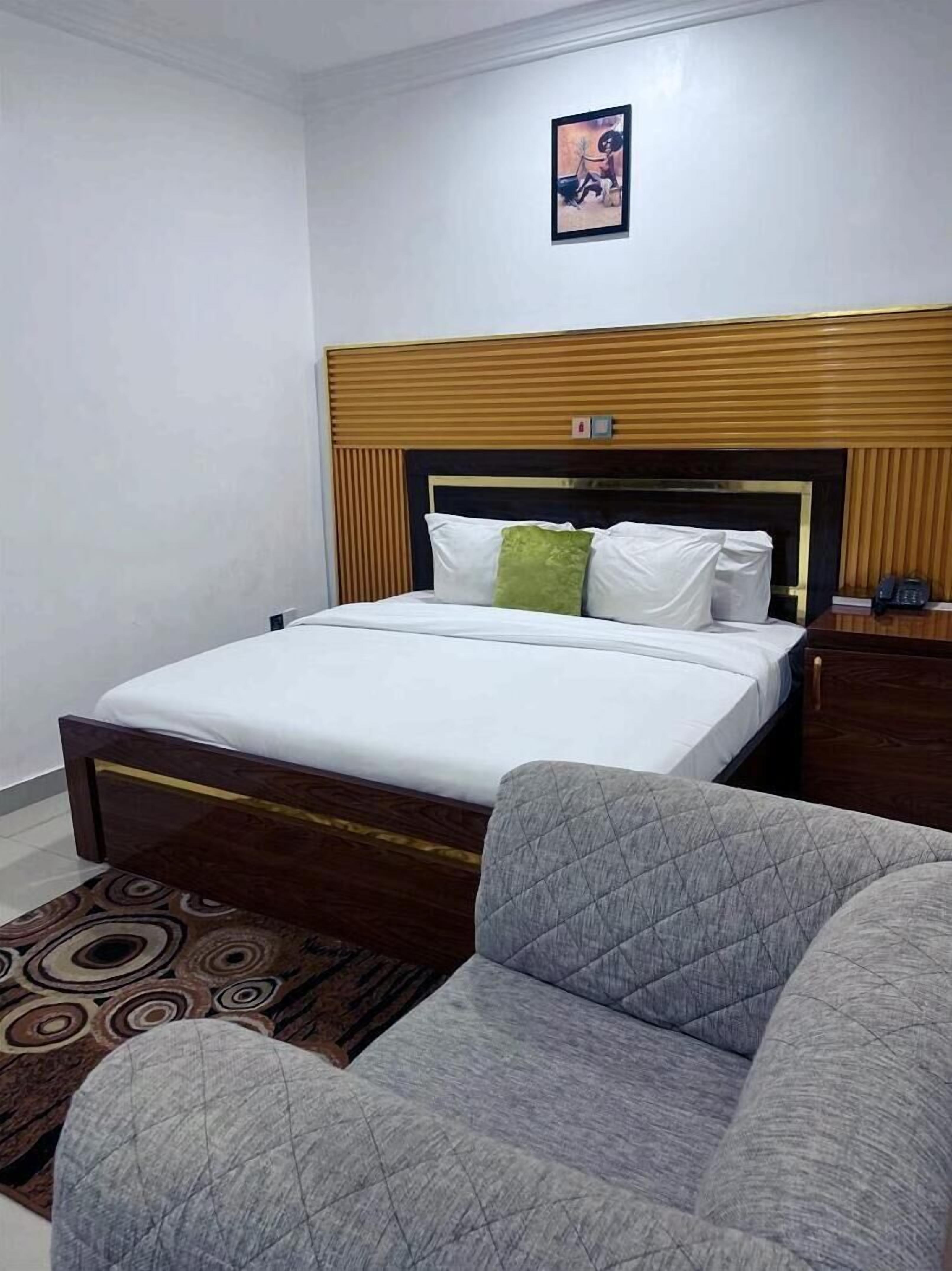 A hotel room with a bed, a nightstand, a telephone, and a picture on the wall.