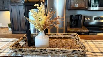 A kitchen counter with a woven tray holding a vase of dried flowers and a black lantern.