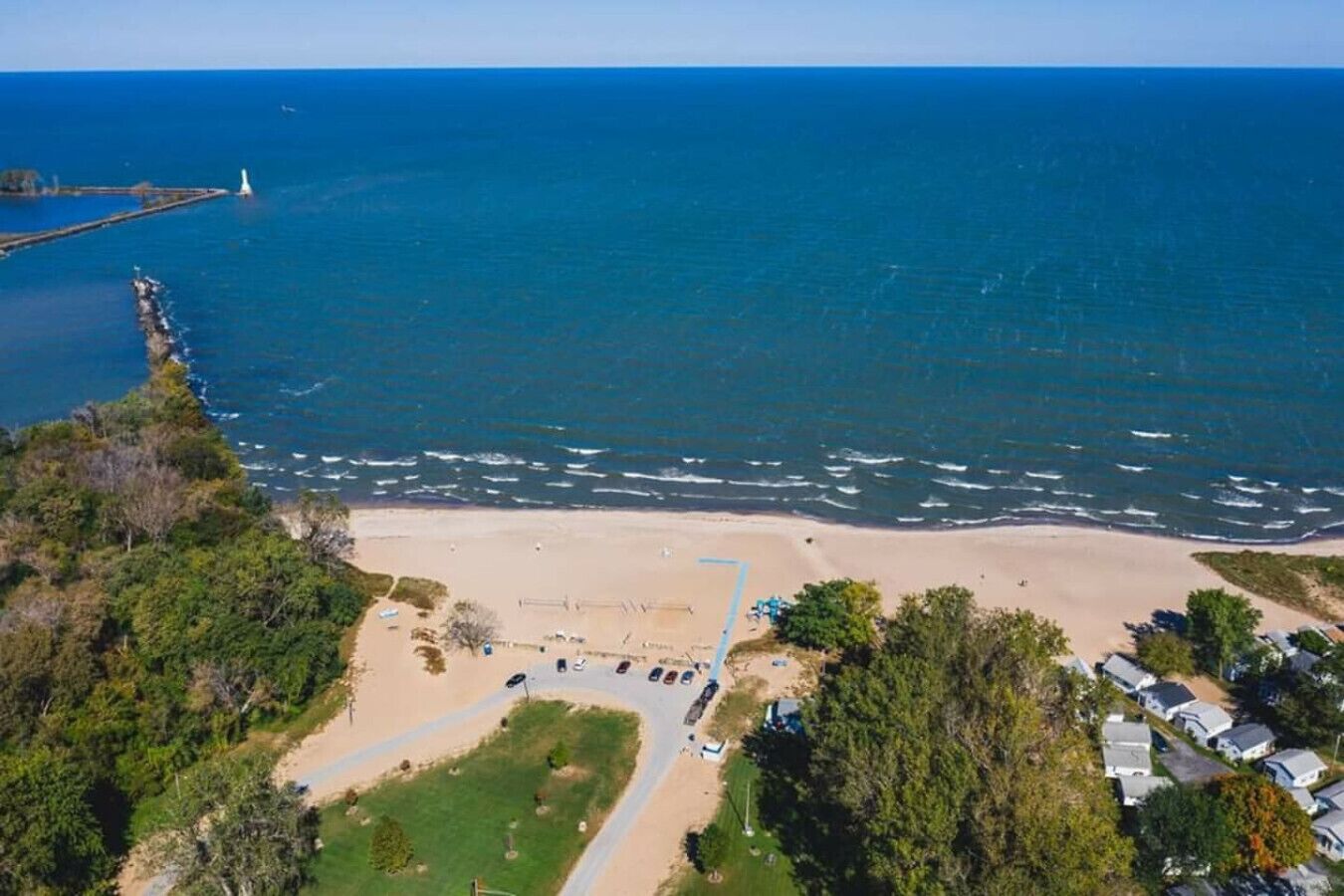 A coastal area with a sandy beach, a lighthouse, and a row of houses.