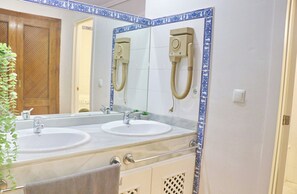 Une salle de bain avec deux lavabos, un miroir, un porte-serviettes et une pomme de douche.