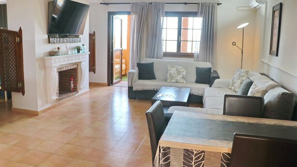 Una sala de estar con chimenea, un sofá, un televisor y un comedor.