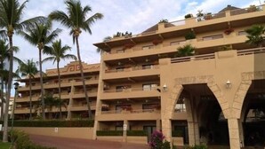 A multi-story hotel with balconies, palm trees, and a central archway entrance. - Paradise to live in! (Nuevo Vallarta)