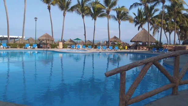 A swimming pool with lounge chairs and palm trees. - Paradise to live in! (Nuevo Vallarta)