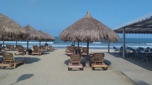 A beach with thatched umbrellas and wooden lounge chairs facing the ocean. - Paradise to live in! (Nuevo Vallarta)