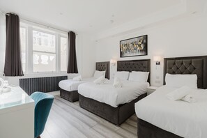 A hotel room with two beds, a desk, and a chair. - The Gate Hotel (London)