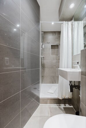 A modern bathroom with a walk-in shower, a sink, and a mirror. - The Gate Hotel (London)