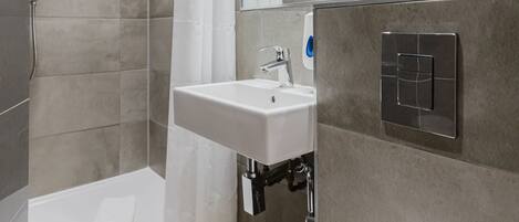 A modern bathroom with a shower, a sink, and a mirror.