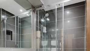 A modern bathroom with a glass-enclosed shower, a white sink, and a large mirror. - The Gate Hotel (London)