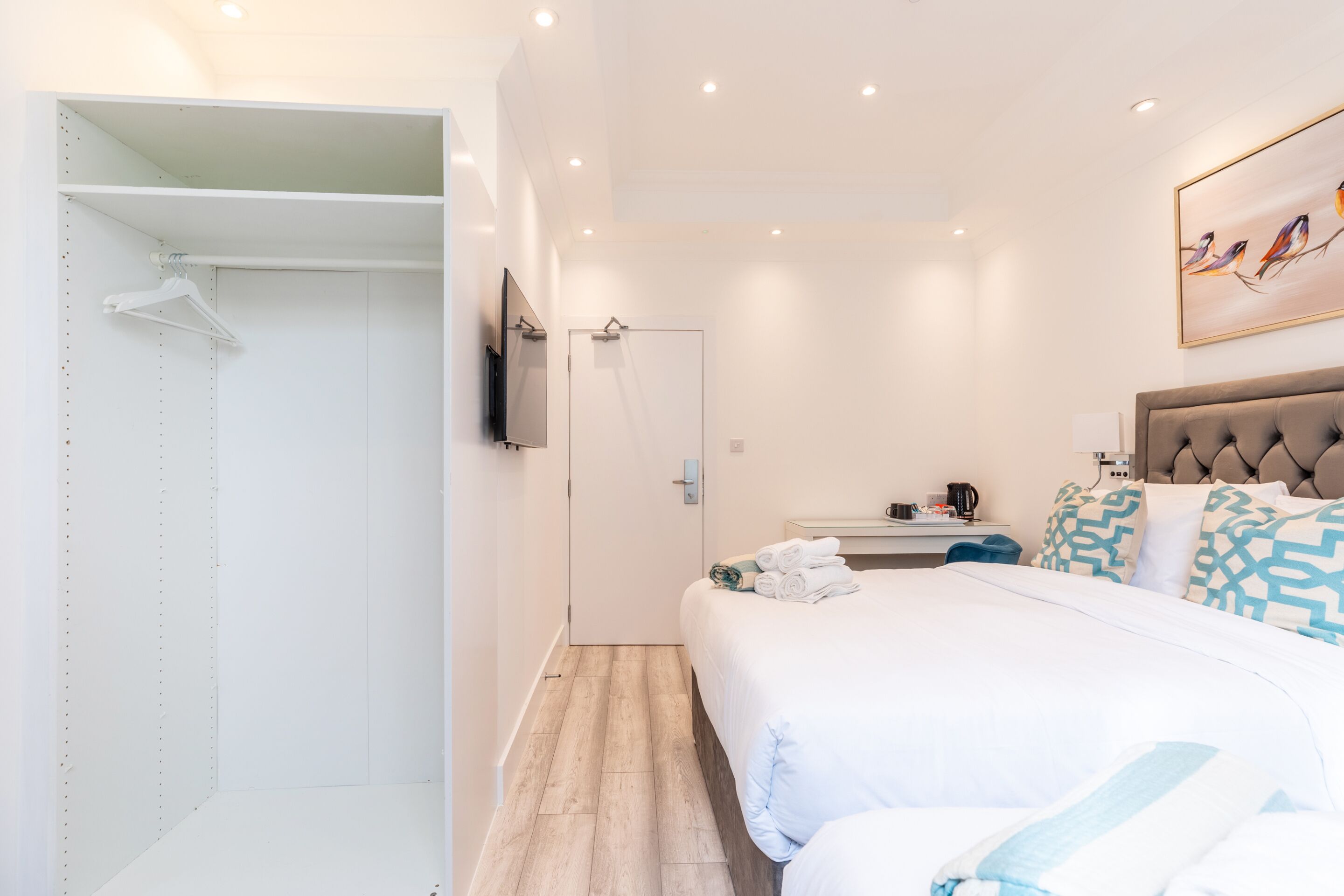 A hotel room with a bed, a wardrobe, a television, and a painting on the wall.