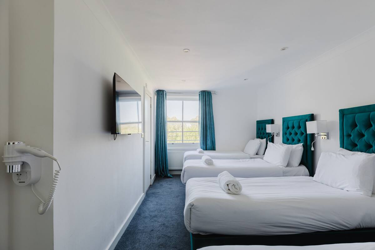 Une chambre d’hôtel avec deux lits, une télévision, un téléphone et une fenêtre avec des rideaux.