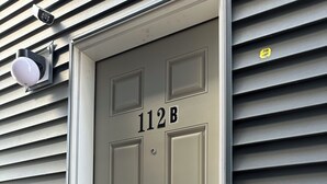 En beige dør med nummeret 112B, en kode lås og et spionhul.
