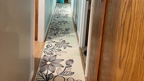 Een gang met een bloemenkleed, houten deuren en een blauwe deur aan het einde.