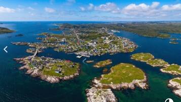 An aerial view of a coastal area with multiple small islands connected by bridges, featuring clear blue waters and a clear sky.
