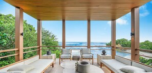 Relax in a serene outdoor space with a panoramic ocean view, comfortable seating, and a central table.