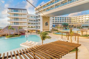 A resort with a swimming pool, lounge chairs, and a multi-story building with balconies. - Sensira Resort & Spa Riviera Maya (Puerto Morelos)