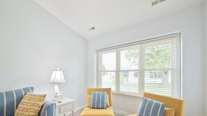 Una habitación con un sofá azul, un sillón amarillo y una pequeña mesa blanca con una lámpara.