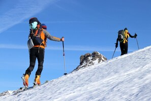 Two individuals hiking on a snow-covered slope with clear skies. - Hostel Élisée Perpignan (Perpignan)