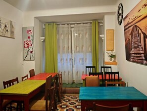 A dining area with a checkered floor, a table with a colorful tablecloth, and chairs. - Hostel Élisée Perpignan (Perpignan)