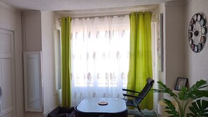 A small, well-lit room with a dining table, chairs, a sofa, and a potted plant. - Hostel Élisée Perpignan (Perpignan)
