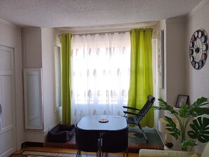 A small, well-lit room with a dining table, chairs, a sofa, and a potted plant. - Hostel Élisée Perpignan (Perpignan)
