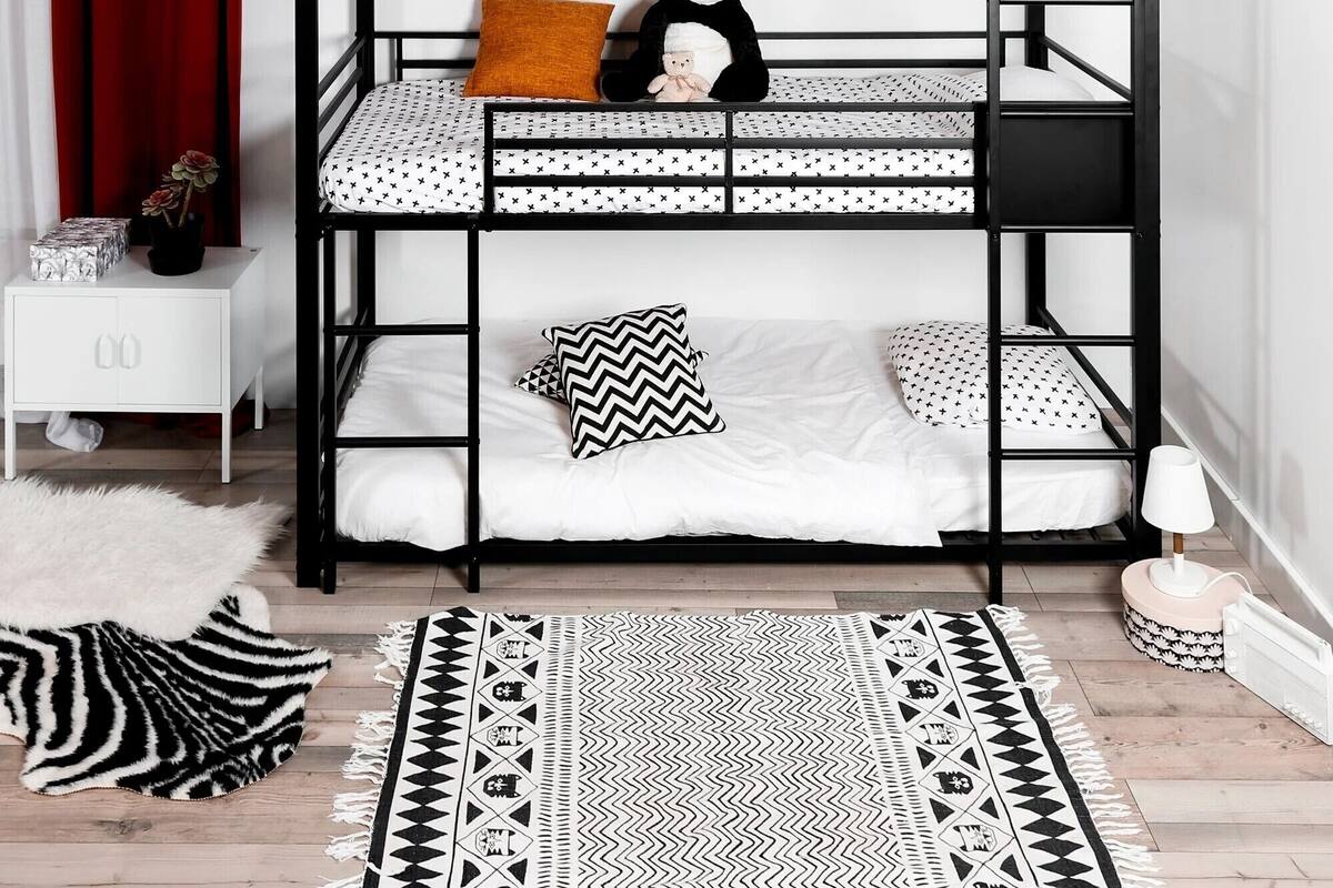 A bunk bed with a patterned mattress, a teddy bear, and a panda toy.