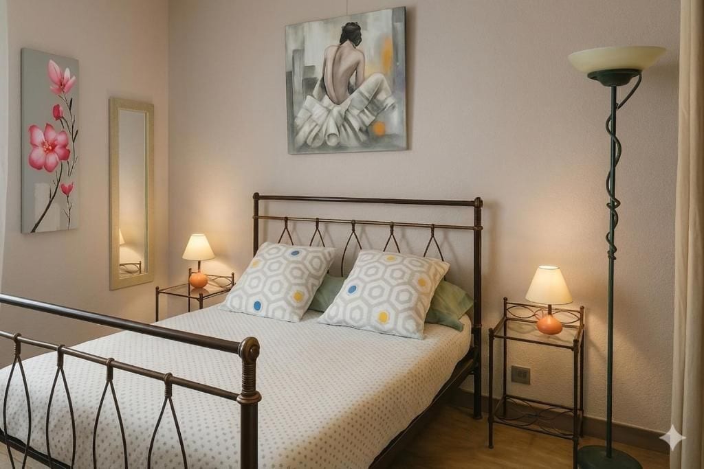 Un dormitorio con cama, dos mesitas de noche, una lámpara de pie y decoración en la pared.