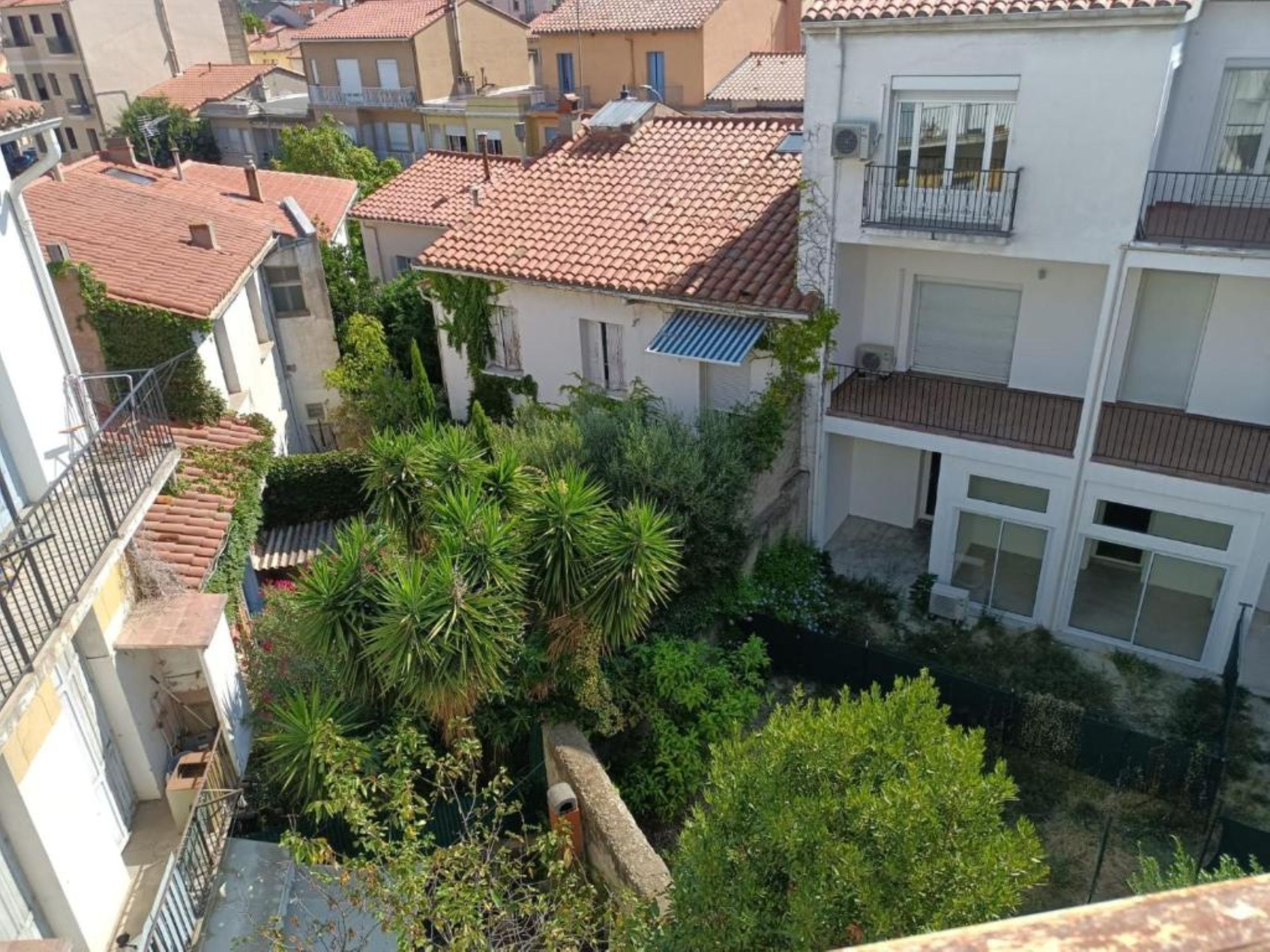 Zona residencial con techos de tejas de arcilla, balcones y abundante vegetación.