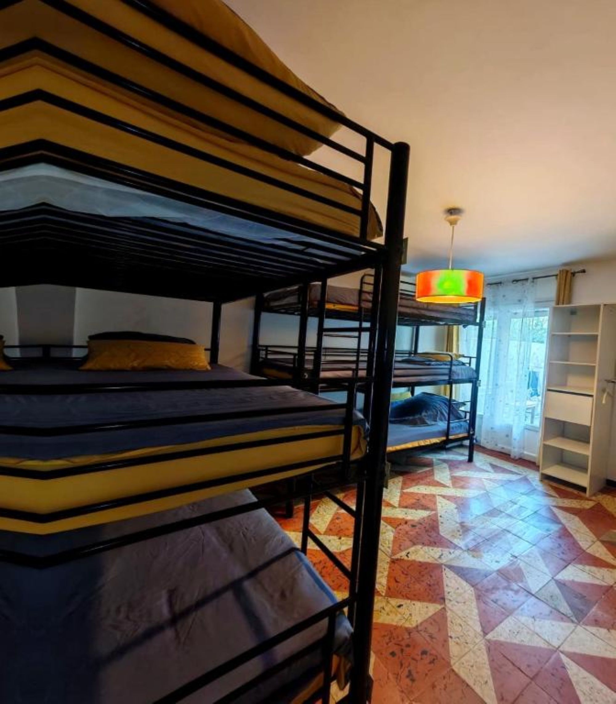 Bunk beds in a room with a patterned floor and a hanging light fixture.