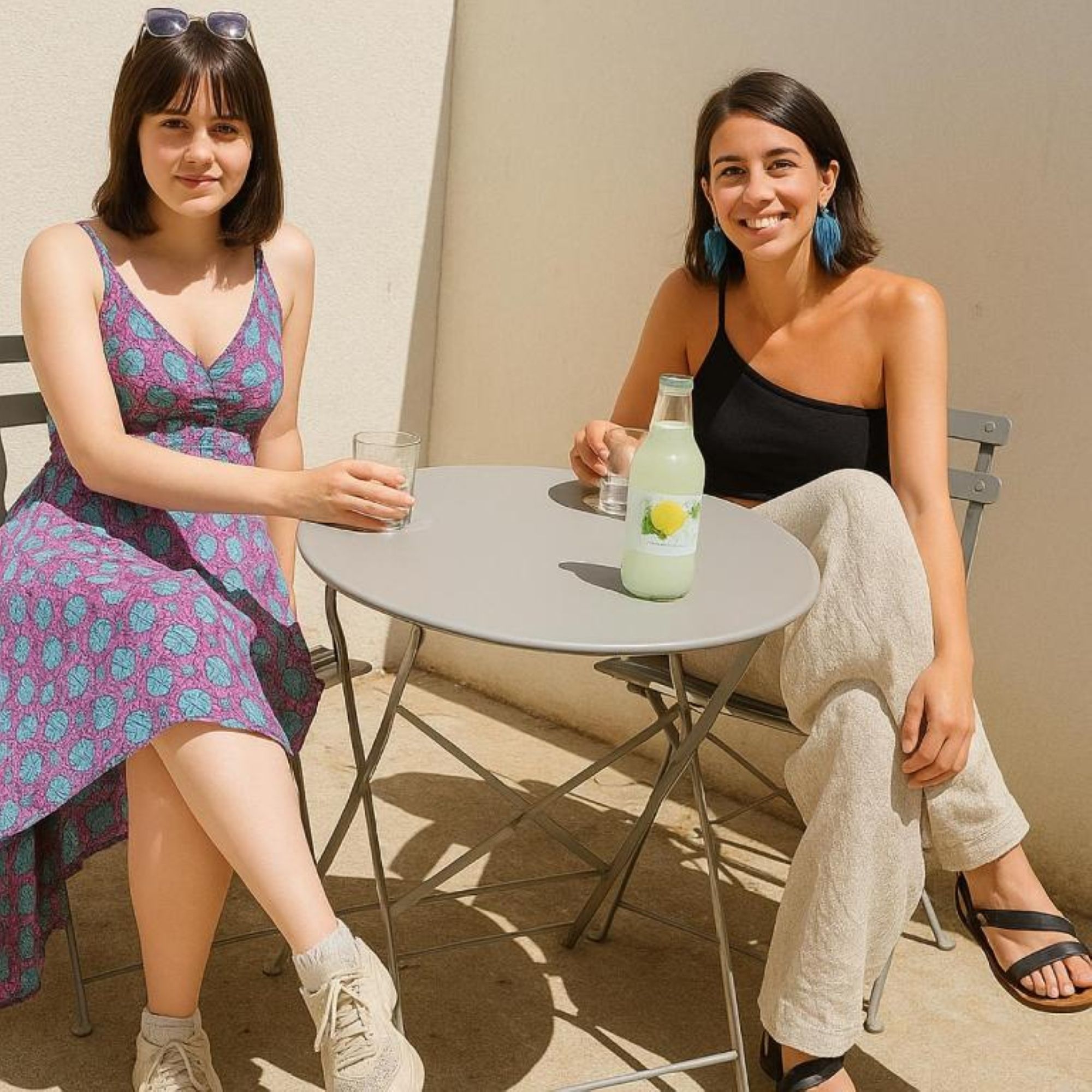Dos personas sentadas en una mesa redonda, con una bebida y una copa.