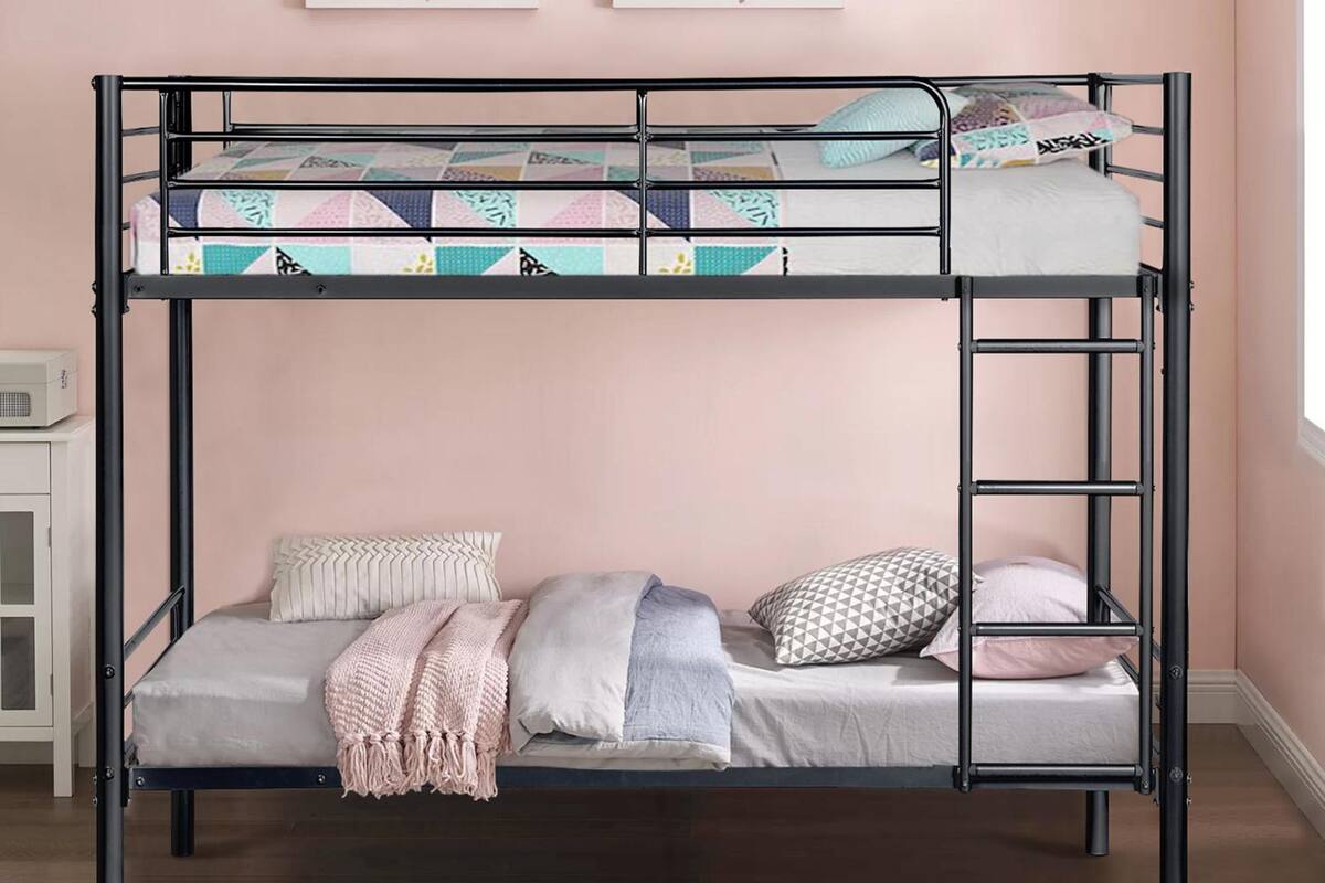 A bunk bed with a lower bunk and a mattress on the upper bunk. There are pillows and a blanket on the lower bunk.
